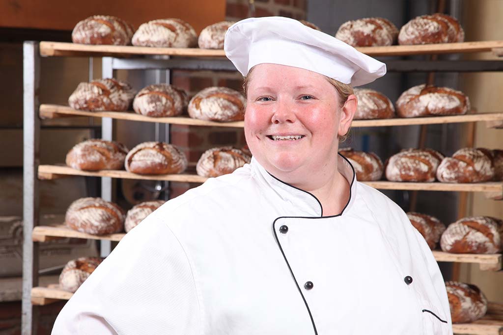 Frau Daniela Grund, Geschäftsführerin der Bäckerei Grund vor einem Brotregal